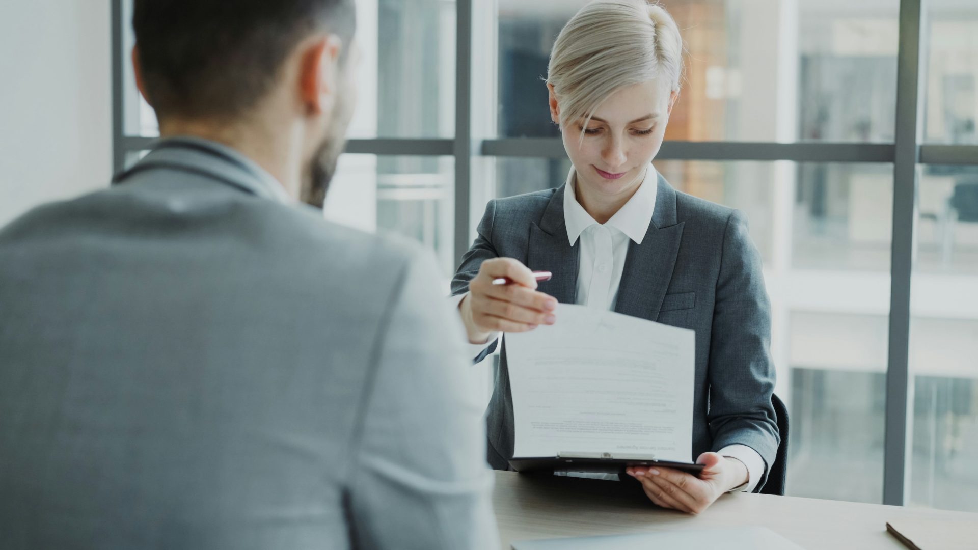 Une femme en tailleur montre un document à un homme.