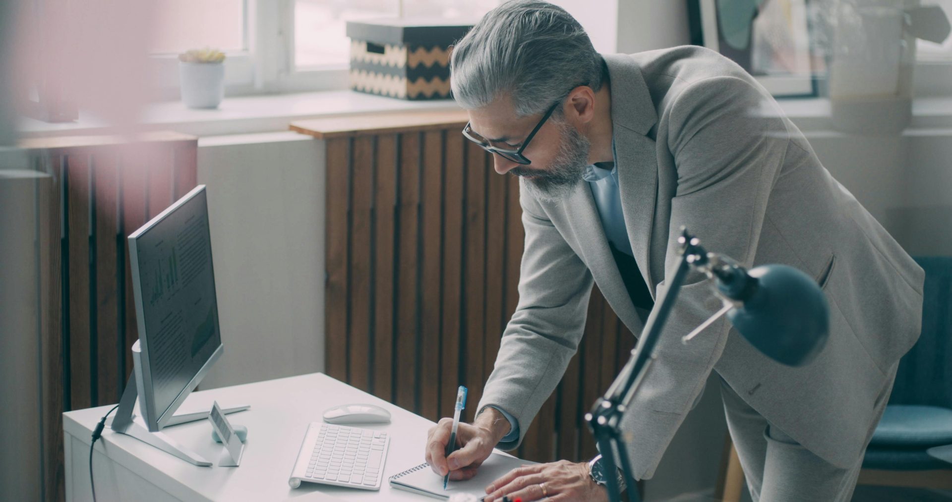 Un homme d'affaires en costume écrit à son bureau dans un environnement de bureau moderne.